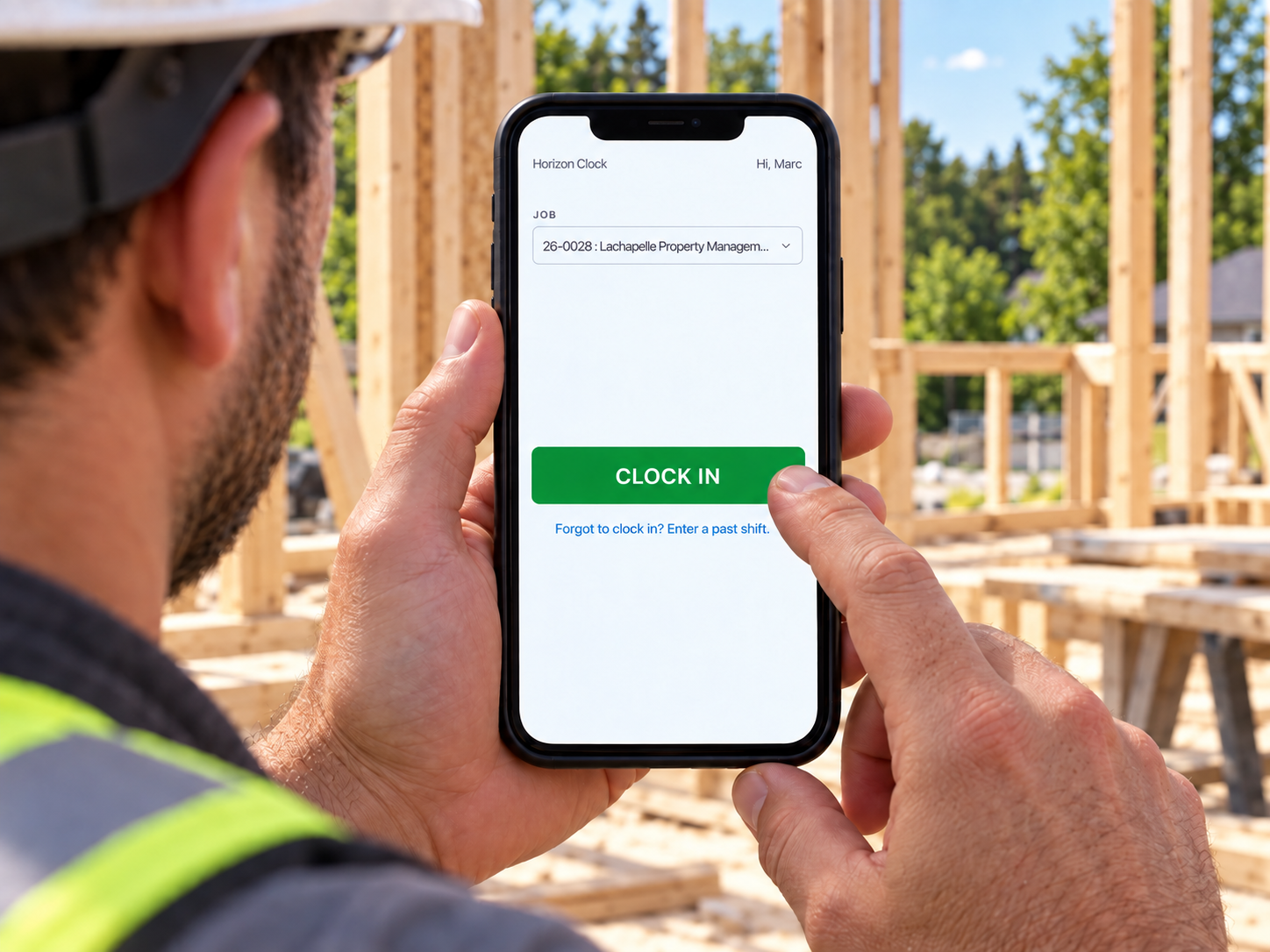 A worker tracks time on a phone at a summer job site.